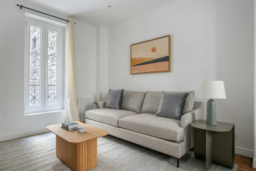 Sala clara con sofá gris y ventana alta
