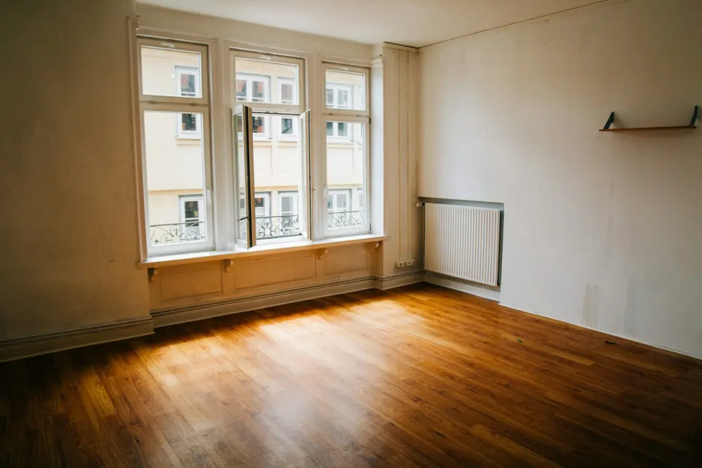 Apartamento vacío con piso de madera y luz de tarde